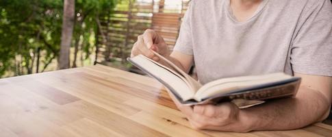 hand- Holding een boek voor lezing Bij huis foto