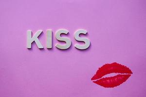 lippen en kus woord met houten brieven Aan de roze achtergrond foto