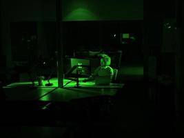 Mens werken Aan computer in donker kantoor foto