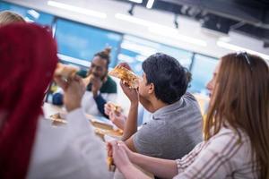 multi-etnisch bedrijf team aan het eten pizza foto