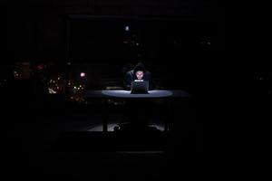 hacker gebruik makend van laptop computer terwijl werken in donker kantoor foto