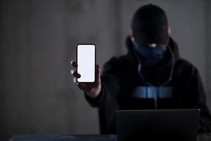 crimineel hacker gebruik makend van laptop computer terwijl werken in donker kantoor foto