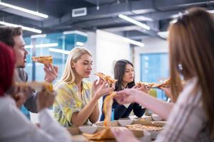 multi-etnisch bedrijf team aan het eten pizza foto