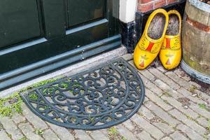 klompen en deurmat bij deur van oud hollands huis foto