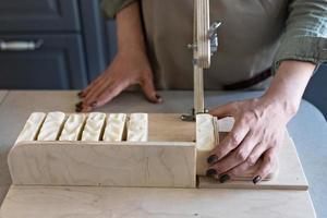 een vrouw maakt handgemaakt natuurlijk zeep.de afgewerkt zeep is besnoeiing in stukken gebruik makend van speciaal machine. huis spa. klein bedrijf foto