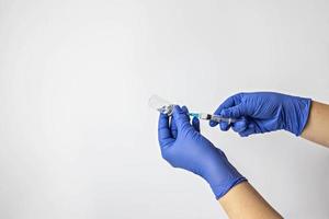 een medisch werker in medische handschoenen trekt een dosis coronavirusvaccin in een spuit. het concept van vaccinatie, immunisatie, preventie van mensen van covid-19 foto