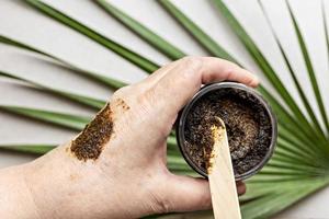 in de hand van een vrouw zit een pot met een bodyscrub gemaakt van natuurlijke ingrediënten. handgemaakte cosmetica. thuis kuuroord. foto