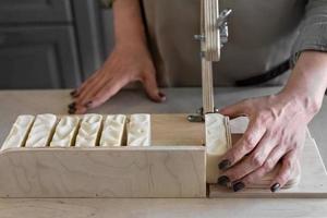 een vrouw maakt handgemaakt natuurlijk zeep.de afgewerkt zeep is besnoeiing in stukken gebruik makend van speciaal machine. huis spa. klein bedrijf foto