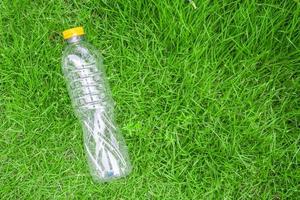 plastic fles Aan groen gras achtergrond recycle en verontreiniging concept foto