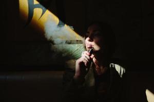 meisje zit en rookt elektronisch sigaret foto
