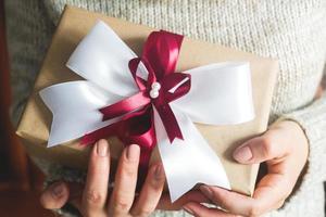 geschenk of Cadeau doos met een groot boog in de handen van een vrouw in een trui. samenstelling voor Kerstmis verjaardag, moeder dag of bruiloft. foto