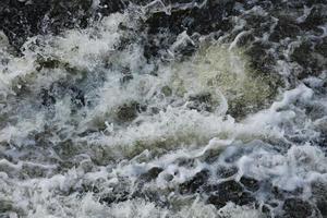 golven van water van de rivier- en de zee ontmoeten elk andere gedurende hoog tij en laag getij. diep blauw stormachtig zee water oppervlakte met wit schuim en golven patroon, achtergrond foto