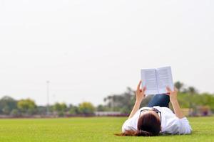 jonge vrouw die een boek in het park leest foto