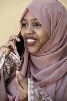 Afrikaanse vrouw gebruik makend van smartphone vervelend traditioneel Islamitisch kleren foto