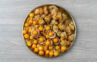 top visie stapel van kaap kruisbes fruit in de goud bord. foto