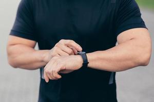 detailopname foto van een mannetje atleet kiezen een sport- programma Aan een geschiktheid armband