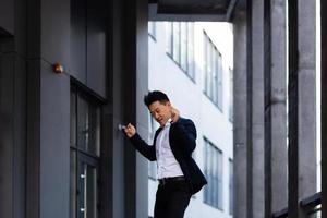 gelukkig en vrolijk Aziatisch zakenman dansen in de buurt de kantoor verheugt zich in zege en succes foto