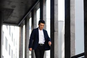 Aziatisch zakenman gaat voor een wandelen in de buurt een modern kantoor centrum in een haast je foto