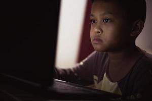 een jongen is aan het studeren online Aan zijn laptop computer Bij huis. foto