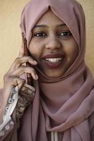 Afrikaanse vrouw gebruik makend van smartphone vervelend traditioneel Islamitisch kleren foto