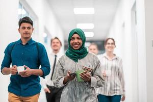 multi-etnisch opstarten bedrijf team wandelen door de gang van de gebouw terwijl komt eraan terug van een koffie breken foto