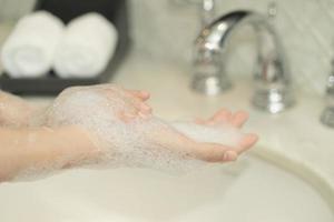 vrouw hand- gebruik zeep en het wassen onder de water tik. hygiëne concept. foto