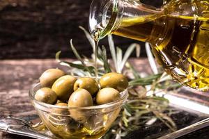 olijfolie en olijven op houten tafel
