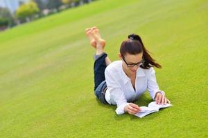 jonge vrouw die een boek in het park leest foto