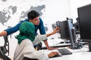 multi-etnisch opstarten bedrijf team Arabisch vrouw vervelend een hijab Aan vergadering in modern Open plan kantoor interieur brainstormen, werken Aan laptop en bureaublad computer. selectief focus foto