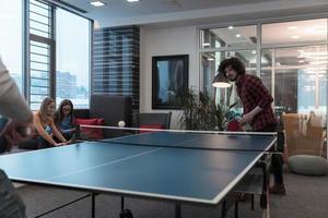 twee jong begin omhoog bedrijf Mens spelen ping pong tennis Bij modern creatief kantoor ruimte mensen groep hebben vergadering en brainstorming in achtergrond foto