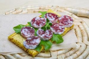 salami belegd broodje Aan houten bord en houten achtergrond foto