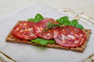 salami belegd broodje Aan houten bord en houten achtergrond foto