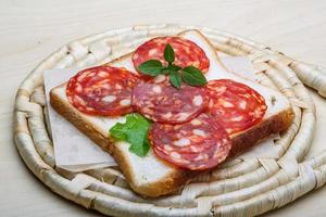 salami belegd broodje Aan houten bord en houten achtergrond foto