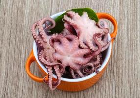 gemarineerde octopus in een kom op houten achtergrond foto