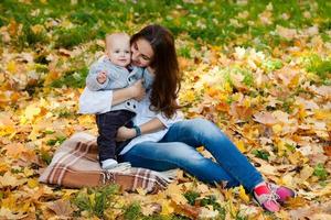 babyjongen in trui spelen met zijn moeder onder pumpki