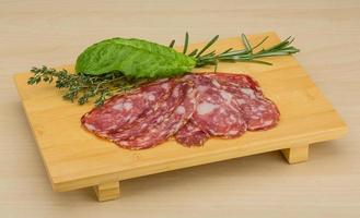 salami Aan houten bord en houten achtergrond foto