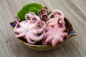 gemarineerde octopus in een kom op houten achtergrond foto