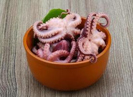 gemarineerde octopus in een kom op houten achtergrond foto