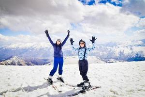 gelukkig opgewonden Kaukasisch moeder en zoon verspreid handen omhoog houding voor sociaal media foto. skiën vakantie in goed, Georgië foto