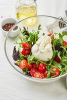 burrata, Italiaans vers kaas gemaakt van room en buffel of koe melk, met tomaat, rucola en rood basilicum salade foto