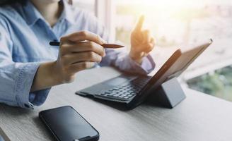 zakenman handen werken met financiën over kosten en rekenmachine en laptop met tablet, smartphone op kantoor in ochtendlicht foto