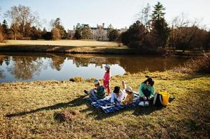 moeder met vier kinderen die picknicken in de buurt van pond in lednice park tegen kasteel, tsjechische republiek. foto