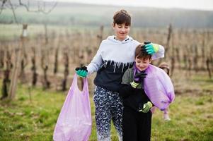 kinderen met uitschot zak verzamelen vuilnis terwijl schoonmaak in de wijngaarden . milieu behoud en ecologie, recyclen. foto