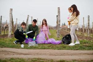 familie met vuilniszak die afval verzamelt tijdens het schoonmaken in de wijngaarden. milieubehoud en ecologie, recycling. foto