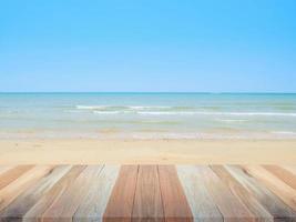 houten tafel top met strand en zee achtergrond, blanco voor ontwerp achtergrond foto