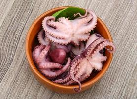 gemarineerde octopus in een kom op houten achtergrond foto