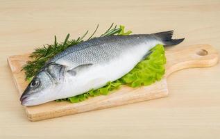 rauw zeebaars Aan houten bord en houten achtergrond foto