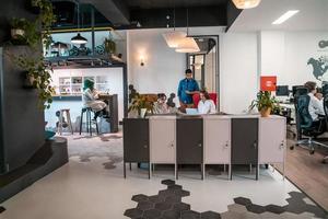 groep van gewoontjes multi-etnisch bedrijf mensen nemen breken van de werk aan het doen verschillend dingen terwijl genieten van vrij tijd in ontspanning Oppervlakte Bij modern Open plan opstarten kantoor foto