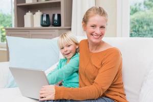 gelukkige moeder en dochter op de bank met laptop foto