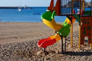 kleurrijk glijbaan Aan de zand van de strand, kinderen spellen foto